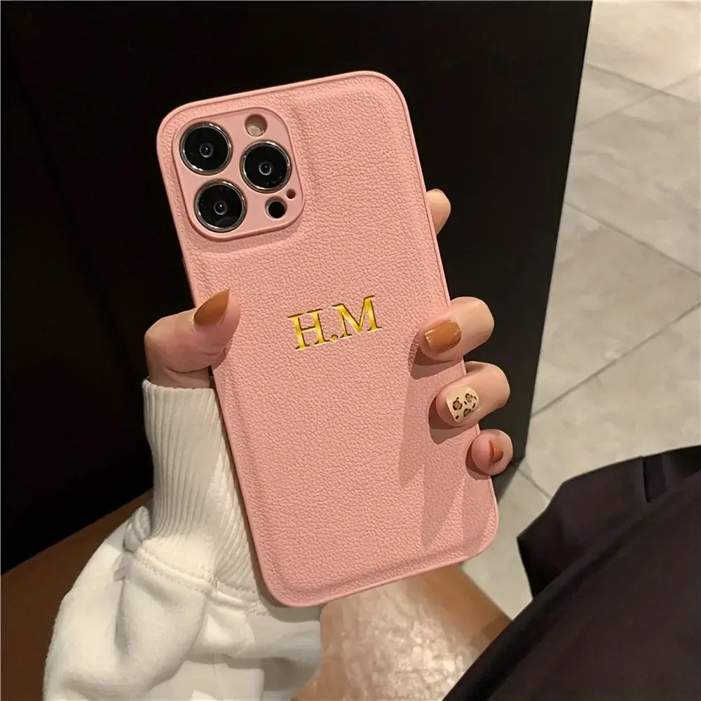 Personalized pink leather iPhone case featuring initials H.M., stylish and custom design for various iPhone models.