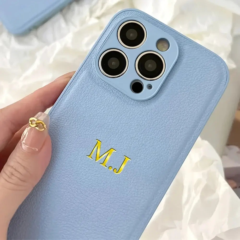 Personalized light blue leather iPhone case with initials M.J embossed in gold.