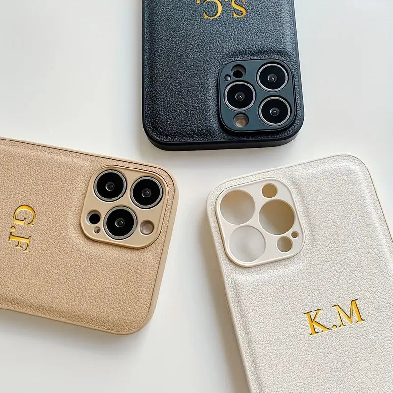 Personalized leather iPhone cases with initials G.E, K.M, and S.C in gold lettering on a neutral background.