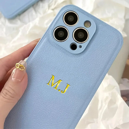 Personalized light blue leather iPhone case with initials M.J embossed in gold.